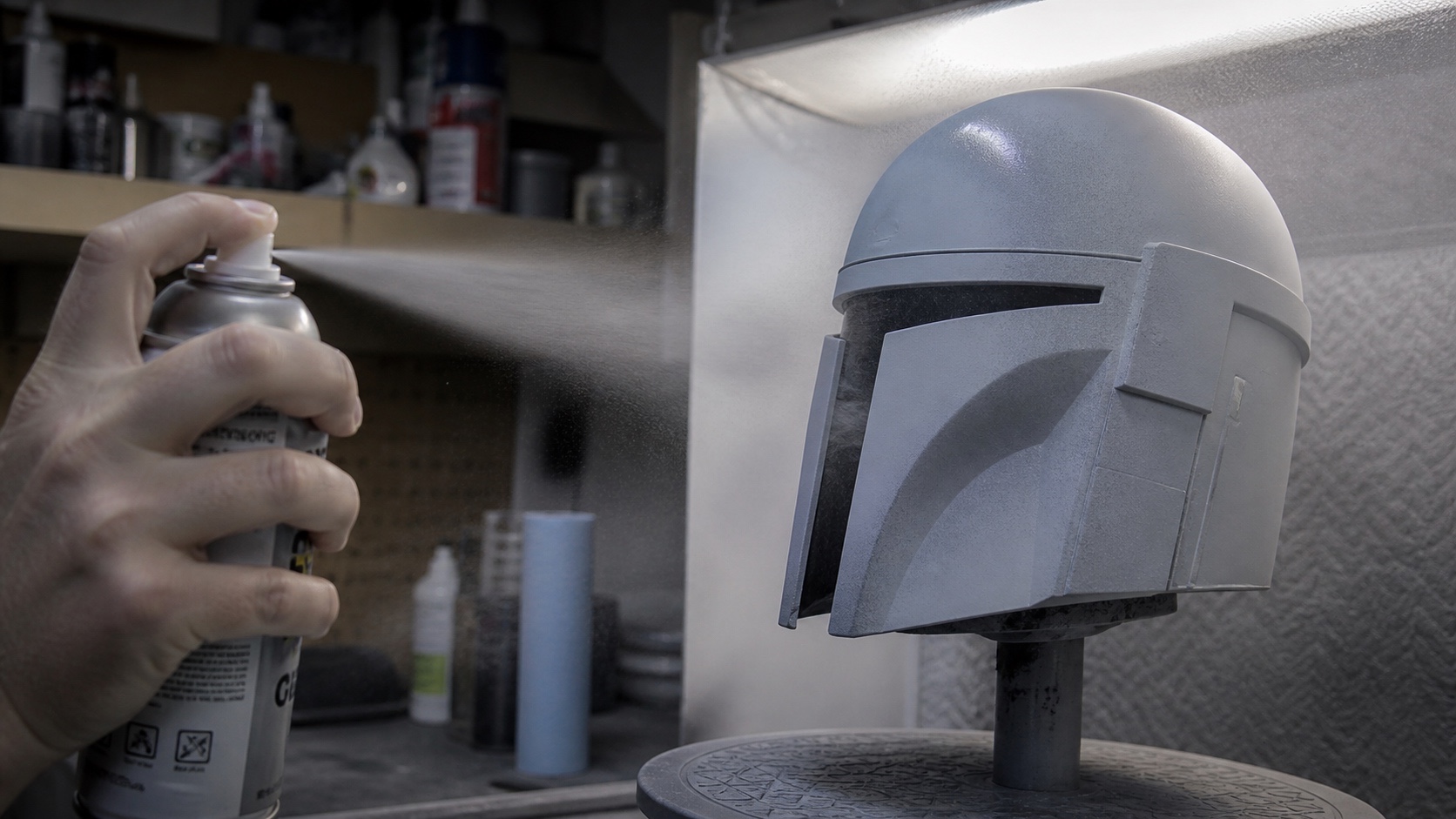 Helmet-shaped 3D print being sprayed with primer in a paint booth